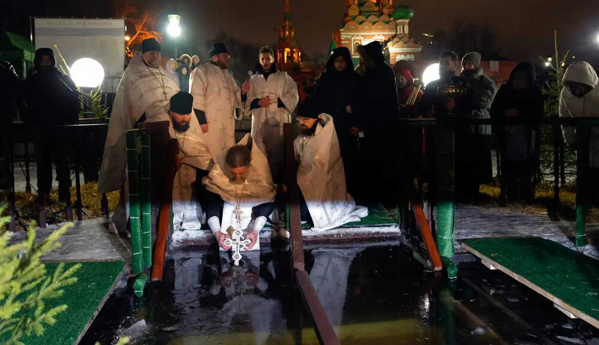 Seorang pendeta Kristen Ortodoks Rusia memberkati air es saat perayaan Epiphany di Gereja Tritunggal Mahakudus, Ostankino, Moskow, Rusia, 18 Januari 2023. Penganut Kristen Ortodoks di Rusia merayakan Hari Raya Epiphany dengan membenamkan diri ke dalam air dingin untuk memperingati pembaptisan Yesus Kristus di Sungai Yordan. (AP Photo/Alexander Zemlianichenko)