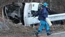 Seorang penyidik berjalan di dekat bangkai bus yang tergelincir di Karuizawa, prefektur Nagano, Jepang, Jumat (15/1). Bus yang membawa pengunjung resor ski itu tergelincir dan menewaskan 14 orang serta melukai 27 lainnya. (AFP PHOTO/Jiji Press JAPAN OUT)