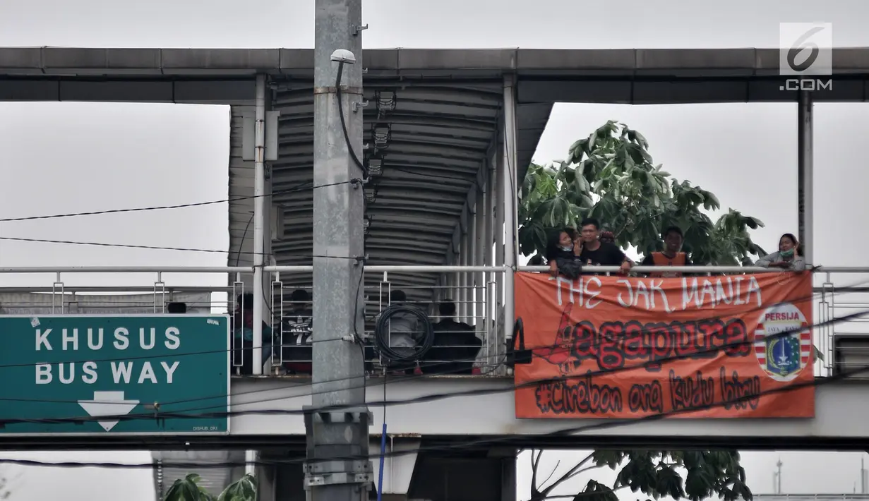 Suporter Persija (The Jakmania) berdiri di dekat spanduk dukungan Persija yang terpasang di Jembatan Penyeberangan Orang (JPO), Jakarta, Minggu (9/12). (Merdeka.com/Iqbal S. Nugroho)