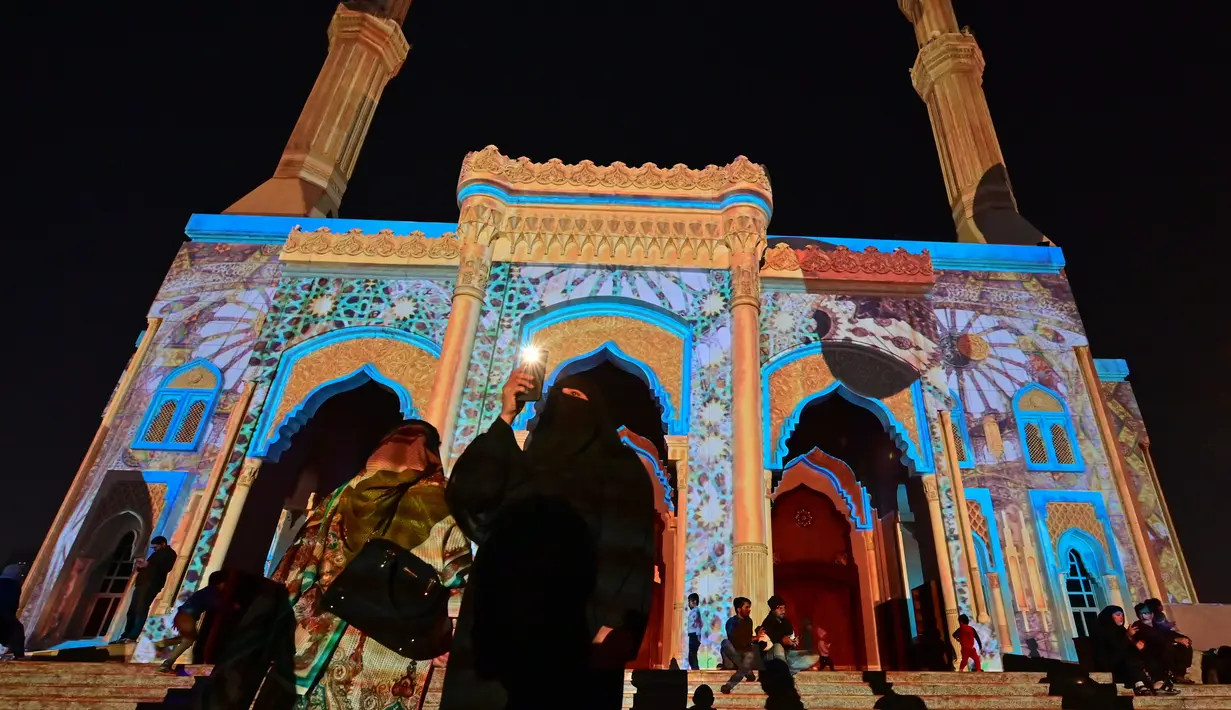 Pengunjung berada di depan Masjid Al-Noor yang diterangi lampu warna-warni selama Festival Cahaya Sharjah di Uni Emirat Arab pada 7 Februari 2020. Festival yang sudah memasuki tahun kesepuluh ini selalu sukses memikat wisatawan lokal maupun asing. (Photo by GIUSEPPE CACACE / AFP)