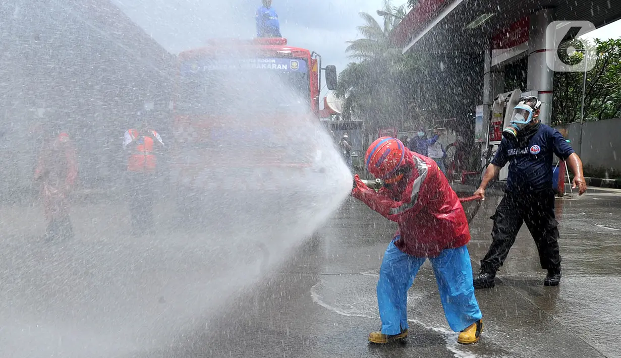 Petugas Pertamina dan Damkar melakukan penyemprotan disinfetaktan di SPBU depan RS Azra, Bogor, Jawa Barat, Jumat (27/03/2020). Hari ini seluruh SPBU di wilayah Bogor dilakukan penyemprotan disinfektan dalam rangka mencegah penyebaran wabah Covid-19. (merdeka.com/Arie Basuki)