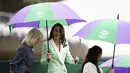Blazernya serasi dengan warna hijau dari payung Wimbledon yang harus dipegangnya sebentar saat ia, seperti penggemar lainnya, berlindung dari hujan musim semi di London. (Zac Goodwin/Pool Photo via AP)