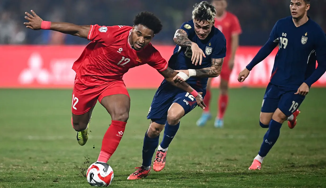 <p>Pemain naturalisasi baru Vietnam, Nguyen Xuan Son (kiri) menggiring bola melewati pemain Thailand, Nicholas Mickelson dalam laga leg pertama final Piala AFF 2024 yang berlangsung di Viet Tri Stadium, Vietnam, Selasa (02/01/2025) waktu setempat. (AFP/Nhac Nguyen)</p>