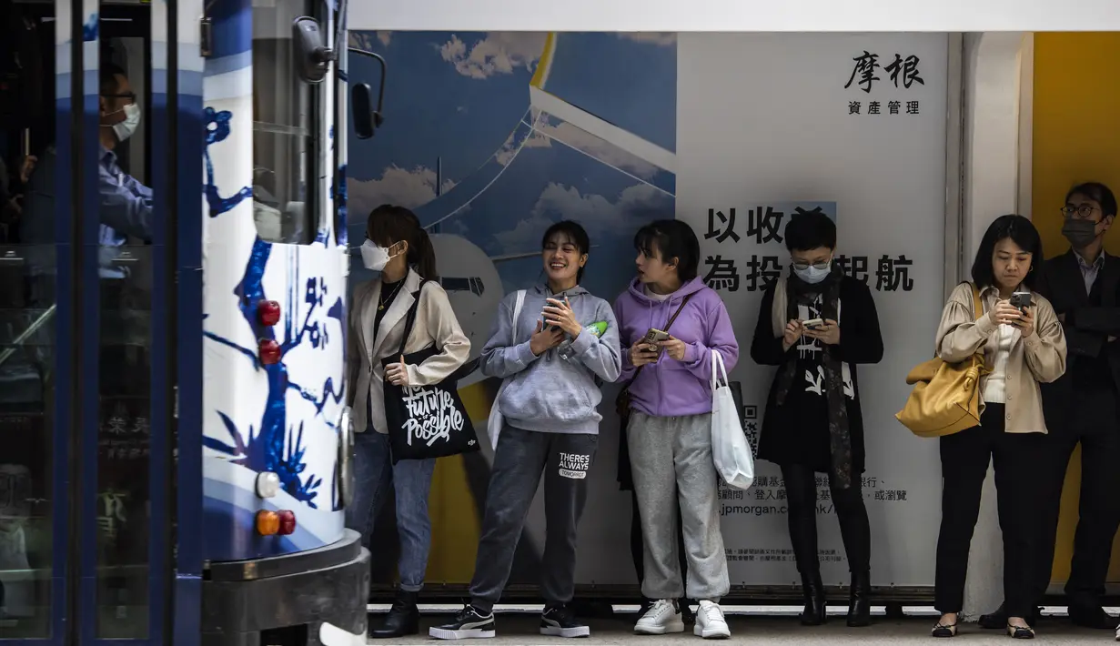 Orang-orang menunggu trem di Hong Kong  (1/3/2023). Pencabutan penggunaan masker sebagai salah satu upaya Hong Kong untuk menarik dan menyambut wisatawan dan pembisnis pasca aturan ketat hampir selama tiga tahun. (AFP/Isaac Lawrence)