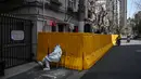Seorang pekerja mengenakan pakaian pelindung menjaga pintu masuk ke lingkungan yang dikunci sebagai tindakan melawan virus corona Covid-19, di distrik Jing'an, di Shanghai (29/3/2022). (AFP/Hector Retamal)