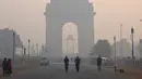 Sejumlah warga beraktivitas di dekat monumen India Gate di tengah kondisi kabut asap tebal di New Delhi (30/10). (AFP Photo/Dominique Faget)