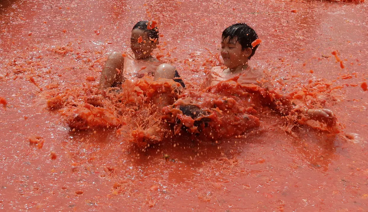 Dua anak laki-laki melompat ke dalam kolam berisi tomat selama Festival Tomat di Hwacheon, Korea Selatan, 5 Agustus 2017. Festival untuk merayakan panen tomat ini berlangsung dari 4 - 7 Agustus. (AP Photo/Ahn Young-joon)