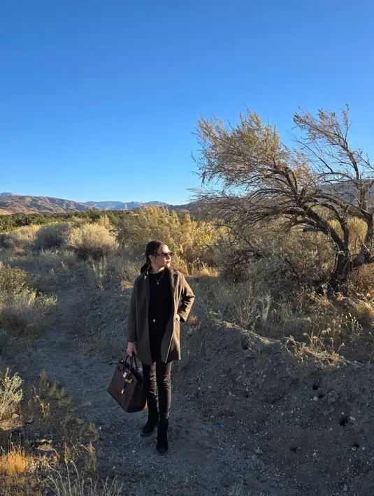 Gaya monokrom kece ala Prilly saat berpose dengan latar alam Las Vegas yang indah. Coat warna coklatnya berpadu serasi dengan tas Hermes Birkin yang dijinjing-nya. [@prillylatuconsina96]