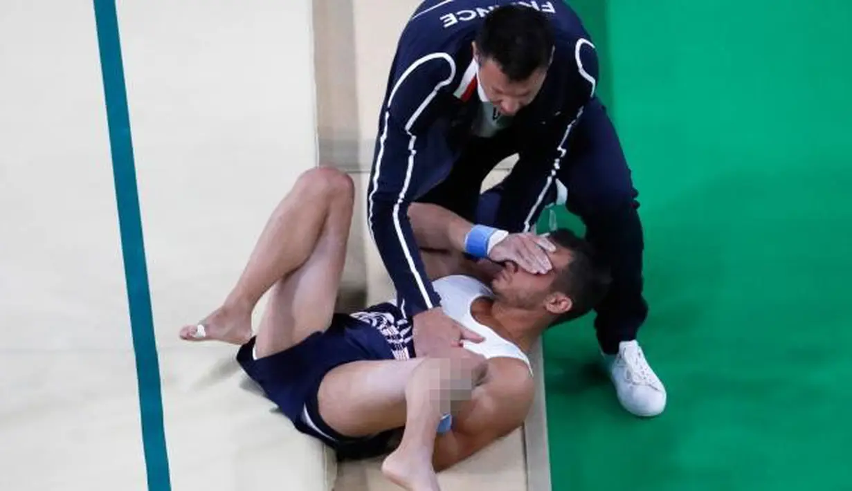 Atlet senam artistik Prancis, Samir Ait Said dibantu tim medis menutup matanya saat tergeletak di lantai dengan posisi kaki patah saat berlaga di Olimpiade Rio 2016 di Rio Olympic Arena, Brasil, Minggu (7/8). (REUTERS/Damir Sagolj)