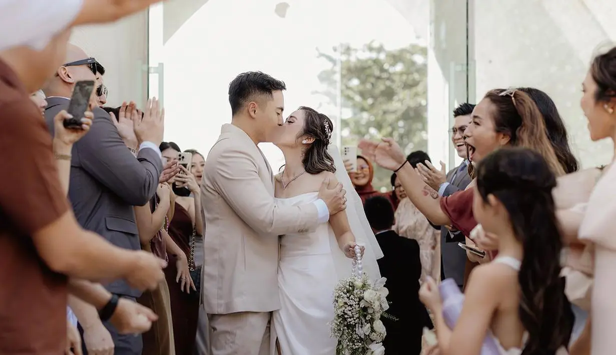 Resmi menjadi suami istri, Gritte dan Arif tengah berciuman dikelilingi oleh para tamu yang hadir. "Mr and Mrs Arif Hidayat ❤️#GRITTEgetmARRIEF," tulis Gritte membagikan potretnya. [Instagram/gritteagathaa]