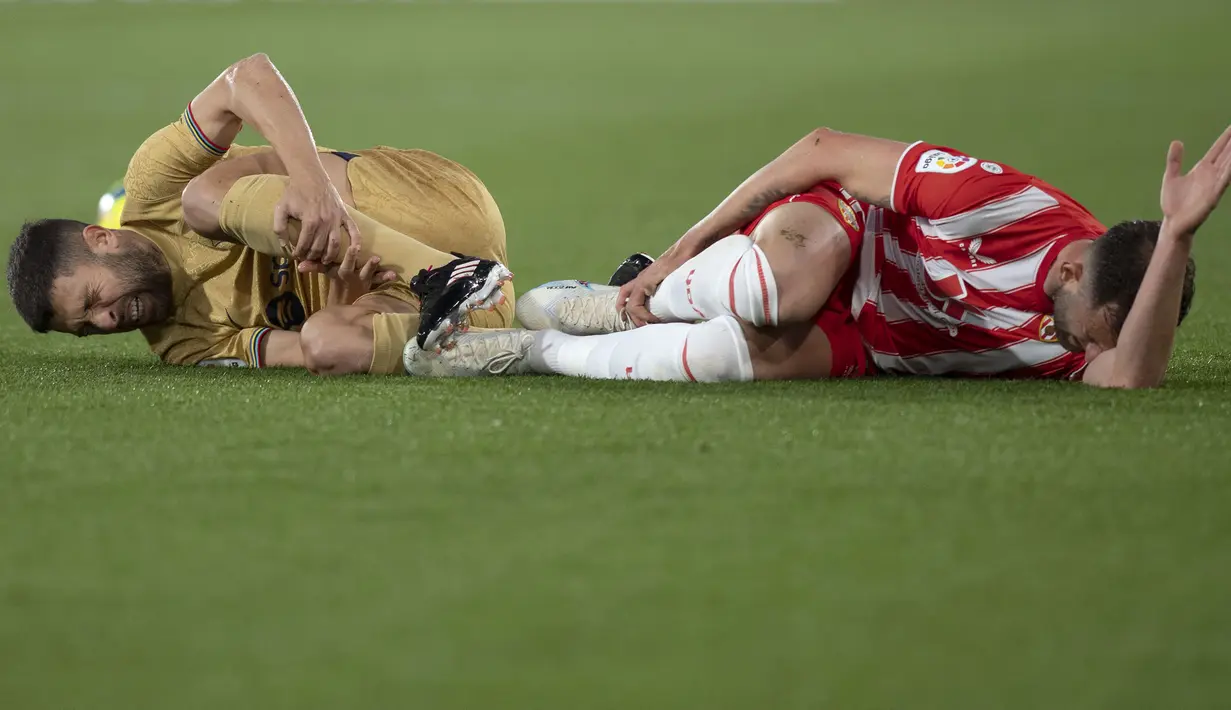 Reaksi kesakitan pemain Barcelona, Jordi Alba (kiri) dan pemain Almeria, Leo Baptistao pada laga lanjutan Liga Spanyol 2022/2023 yang berlangsung di Power House Stadium, Senin (27/02/2023) dini hari WIB. (AFP/Jorge Guerrero)