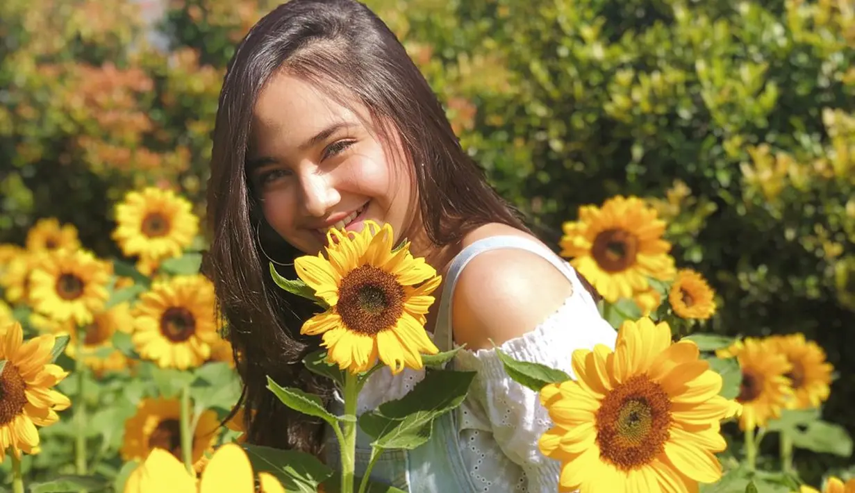 Senyum manis perempuan yang dekat dengan Rizky Nazar juga begitu terpancarkan. Senyum manisnya ini dipuji netizen cantik menawan. Berfoto di taman bunga matahari membuatnya terlihat tampak begitu cerah. (Liputan6.com/IG/@syifahadjureal)