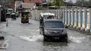Sebuah mobil melintas di jalan yang tergenang air di Muara Angke, Jakarta, Senin (2/1). Rencananya Pemprov DKI akan membuat tanggul penahan air rob di kawasan tersebut. (Liputan6.com/Faizal Fanani)