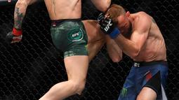 Conor McGregor (kiri) menghantamkan lututnya ke wajah Donald 'Cowboy' Cerrone pada pertarungan kelas welter UFC 246 di T-Mobile Arena, Las Vegas, Amerika Sertikat, Sabtu (18/1/2020). McGregor mengalahkan Cowboy pada detik ke-40. (Steve Marcus/Getty Images/AFP)