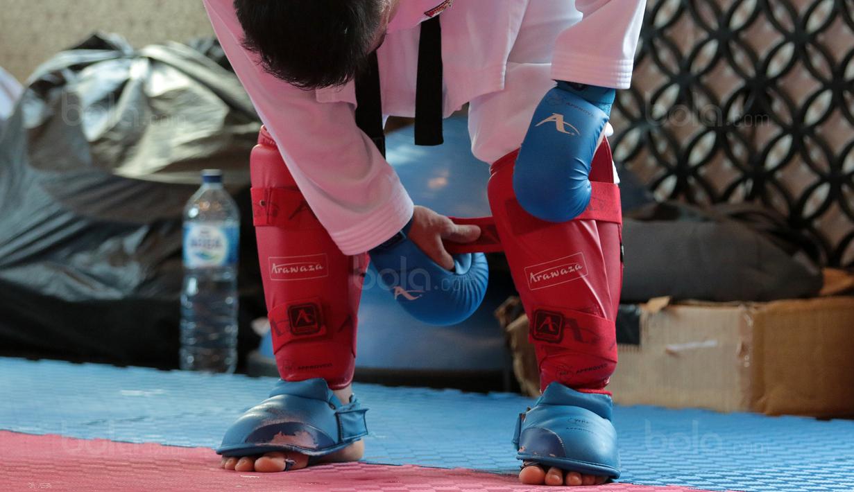 Seorang Karateka Indonesia membetulkan pelindung kaki saat berlatih sparring sebagai persiapan bertanding pada ajang SEA Games 2017 di The Belezza, Permata Hijau, Jakarta, Senin (07/8/2017). (Bola.com/Nicklas Hanoatubun)