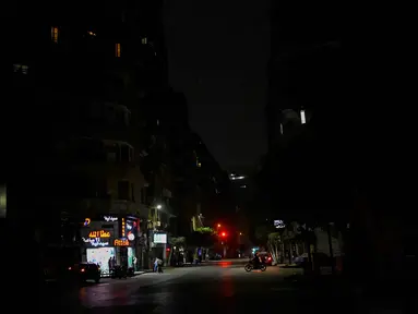 Warga berdiri di depan toko-toko yang tutup lebih awal karena pemberlakuan jam malam yang diperintahkan pemerintah untuk mengurangi biaya energi di pusat kota Kairo, Mesir, pada Kamis 2 April 2026. Pemerintah Mesir memberlakukan pembatasan jam operasional bagi berbagai sektor bisnis sebagai langkah darurat untuk mengatasi krisis energi. (Khaled DESOUKI/AFP)