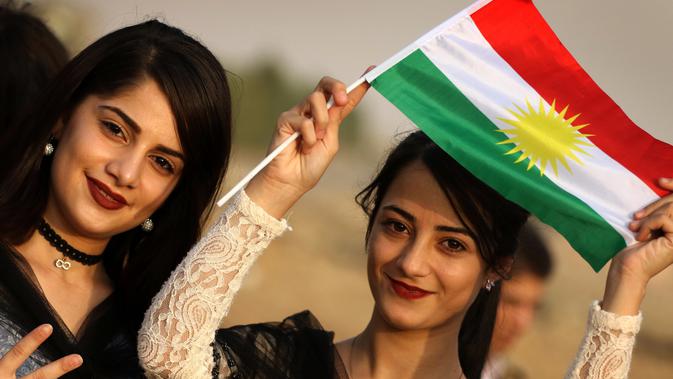 Seorang gadis Kurdi Iran memegang bendera Kurdi saat mengampanyekan referendum untuk kemerdekaan di kota Bahirka, Irak Utara (21/9). Mereka meminta referendum untuk menentukan kemerdekaan etnis Kurdi di Irak. (AFP Photo/Safin Hamed)