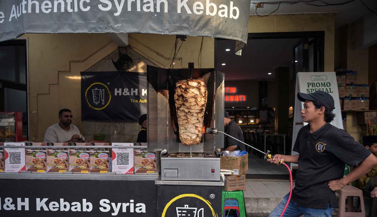 Berlokasi di sekitar area religi bersejarah, pasar ini menawarkan kuliner khas Timur Tengah, seperti, kurma, roti maryam, dan kebab, tersedia pula jajanan Nusantara. Tampak dalam foto, seorang penjual kebab memanaskan daging sambil menunggu pelanggan selama bulan suci Ramadan di dekat Masjid Sunan Ampel, Surabaya, Jawa Timur, pada Minggu 8 Maret 2026. (JUNI KRISWANTO/AFP)