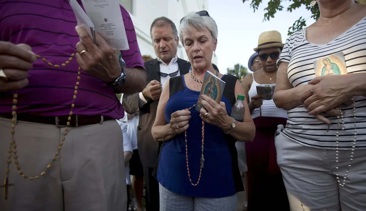 Jemaat berdoa dengan rosario di luar Gereja Emanuel, Charleston, Amerika Serikat, Minggu (21/6/2015). Gereja tersebut dibuka kembali untuk ratusan jemaat yang berkabung usai penembakan yang menewaskan 9 orang. (REUTERS/Carlo Allegri) 