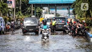 Kendaraan bermotor melintasi jalan yang tergenang air rob (banjir pasang air laut) di Kawasan Pasar Ikan Muara Baru, Jakarta, Kamis (4/6/2020). Banjir rob di Pelabuhan Muara Baru tersebut terjadi akibat cuaca ekstrem serta pasangnya air laut. (Liputan6.com/Faizal Fanani)