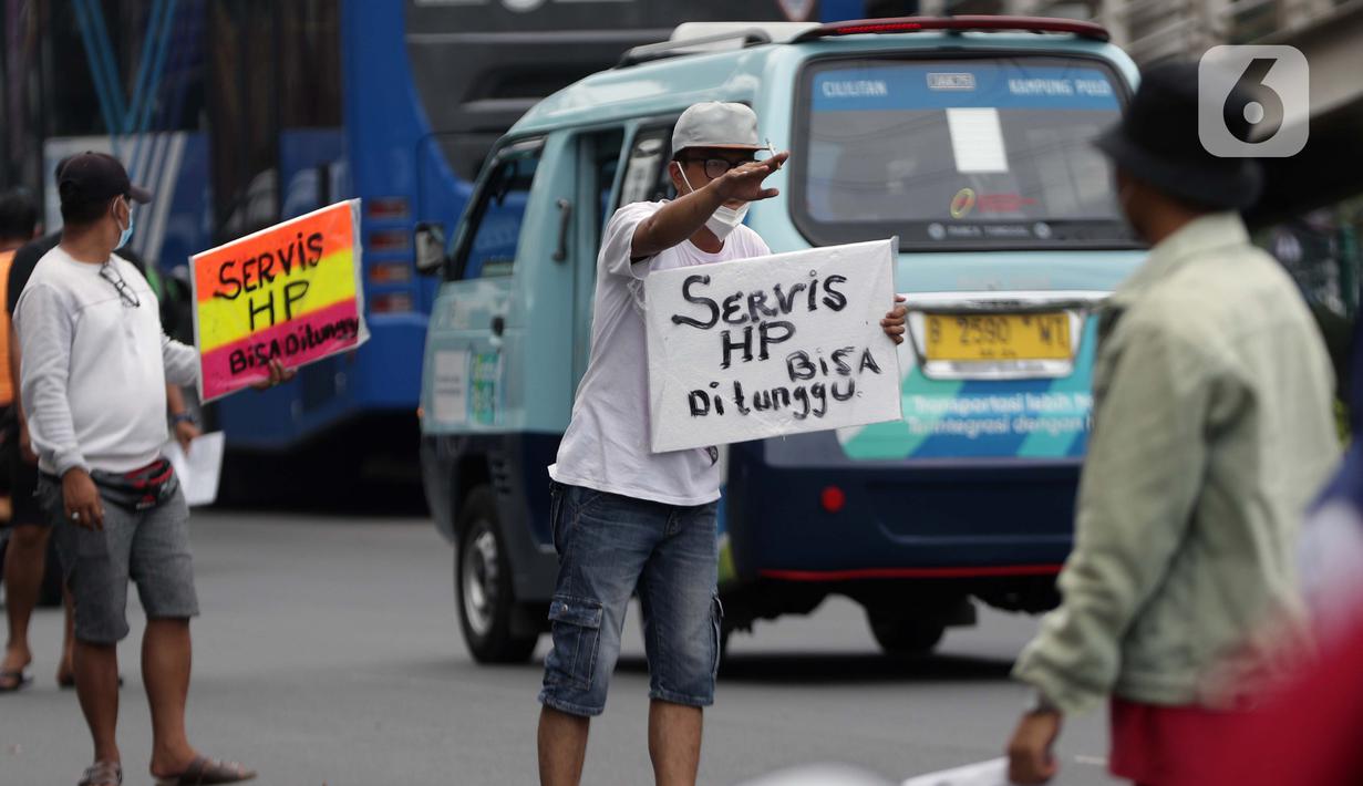 Penjual jasa perbaikan telepon genggam menawarkan jasa di pinggir jalan Mayjen Sutoyo depan Mall Pusat Grosir Cililitan (PGC), Jakarta, Rabu (14/7/2021). Kios yang biasa mereka tempati tutup seiring penutupan Mall PGC selama pemberlakuan PPKM Darurat Jawa-Bali. (Liputan6.com/Helmi Fithriansyah)