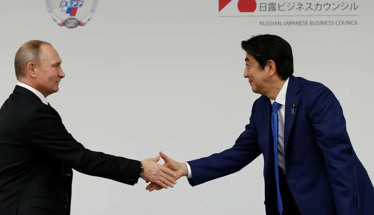 Presiden Rusia Vladimir Putin (Kiri) dan PM Jepang Shinzo Abe berjabat tangan saat preskon di Tokyo, Jepang, Jumat (16/12). Selain membahas soal wilayah sengketa, kedua belah pihak juga membahas situasi di semenanjung Korea. (REUTERS / Kim Kyung-Hoon)