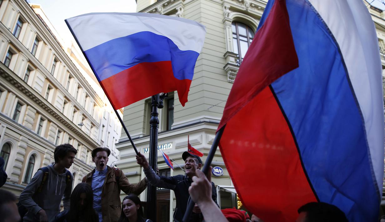 Suporter Rusia mengibarkan bendera menyambut gelaran Piala Dunia di Jalan Nikolskava, Moskow, Rabu (13/6/2018). Piala Dunia 2018 akan berlangsung pada 14 Juni hingga 15 Juli mendatang. (AP/Rebecca Blackwell)
