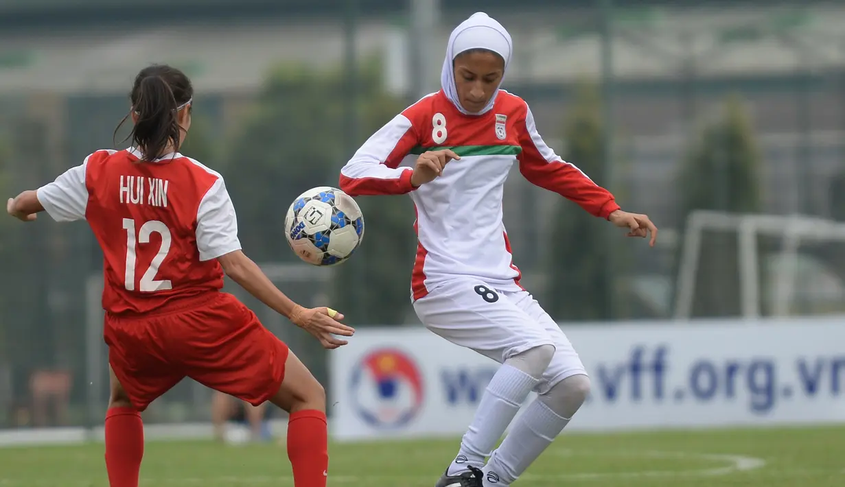 Pemain wanita Iran, Sabnam Behesht (kanan) berebut bola dengan pemain Singapura Ho Hui Xin selama kualifikasi Kejuaraan Piala Asia Wanita AFC tahun 2018 di Hanoi, Vietnam (5/4). (AFP Photo / Hoang Dinh Nam)