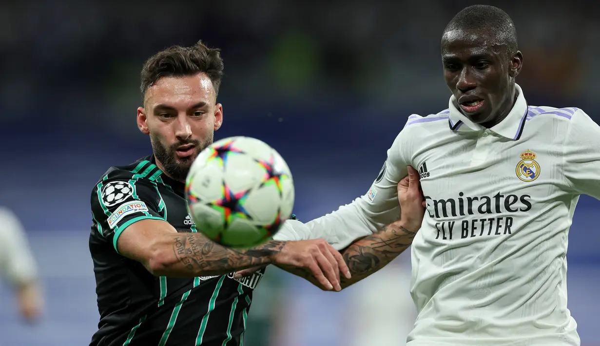 Bek Real Madrid, Ferland Mendy (kanan) berebut bola dengan striker Glasgow Celtic, Sead Haksabanovic pada laga fase Grup E Liga Champions 2022/2023 di Santiago Bernabeu Stadium, Madrid (2/11/2022). Ferland Mendy yang kini memasuki musim keempat bersama Real Madrid sejak didatangkan pada 2019/2020 hingga kini telah tampil dalam 130 laga di semua ajang dengan torehan 5 gol dan 10 assist. (AFP/Thomas Coex)