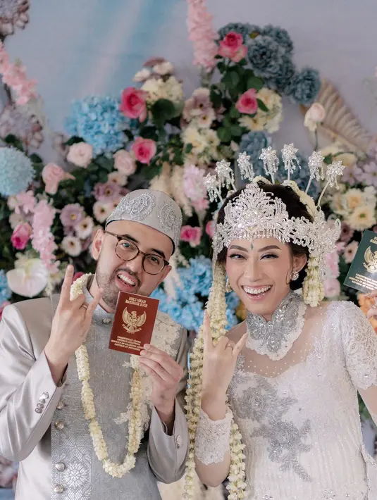 Senyum bahagia Kemal dan Yumi setelah sah resmi menjadi suami istri. Keduanya menunjukkan buku nikah sambil memberikan tanda metal. [Instagram/clinovic_photography]