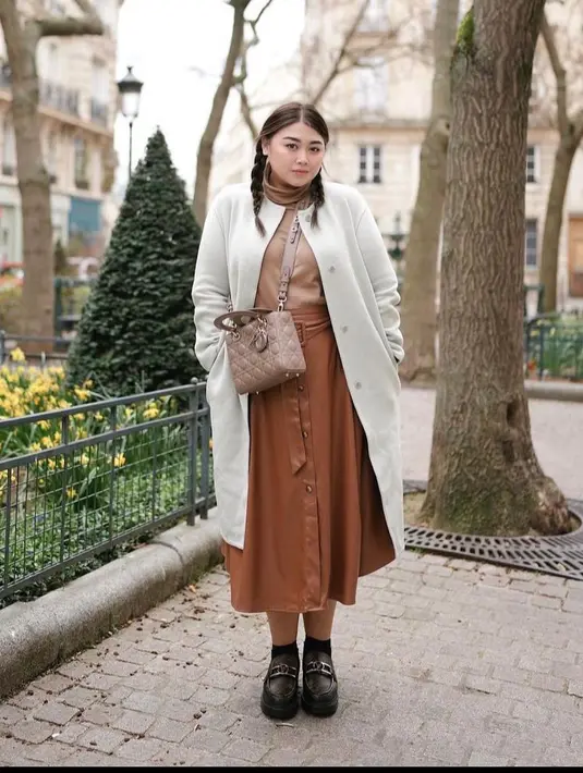 Layering outfit bisa jadi opsi untuk siasati tubuh berisi. Kombinasikan turtleneck dengan long outer, dan rok. (Instagram/clarissaputri_).