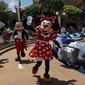 Karakter Minnie dan Mickey Mouse melambai kepada pengunjung di Disneyland Hong Kong, Kamis (18/6/2020). Disneyland Hong Kong kembali beroperasi pada 18 Juni 2020 dengan menerapkan sejumlah protokol kesehatan baru untuk mencegah penyebaran COVID-19. (AP Photo/Kin Cheung)