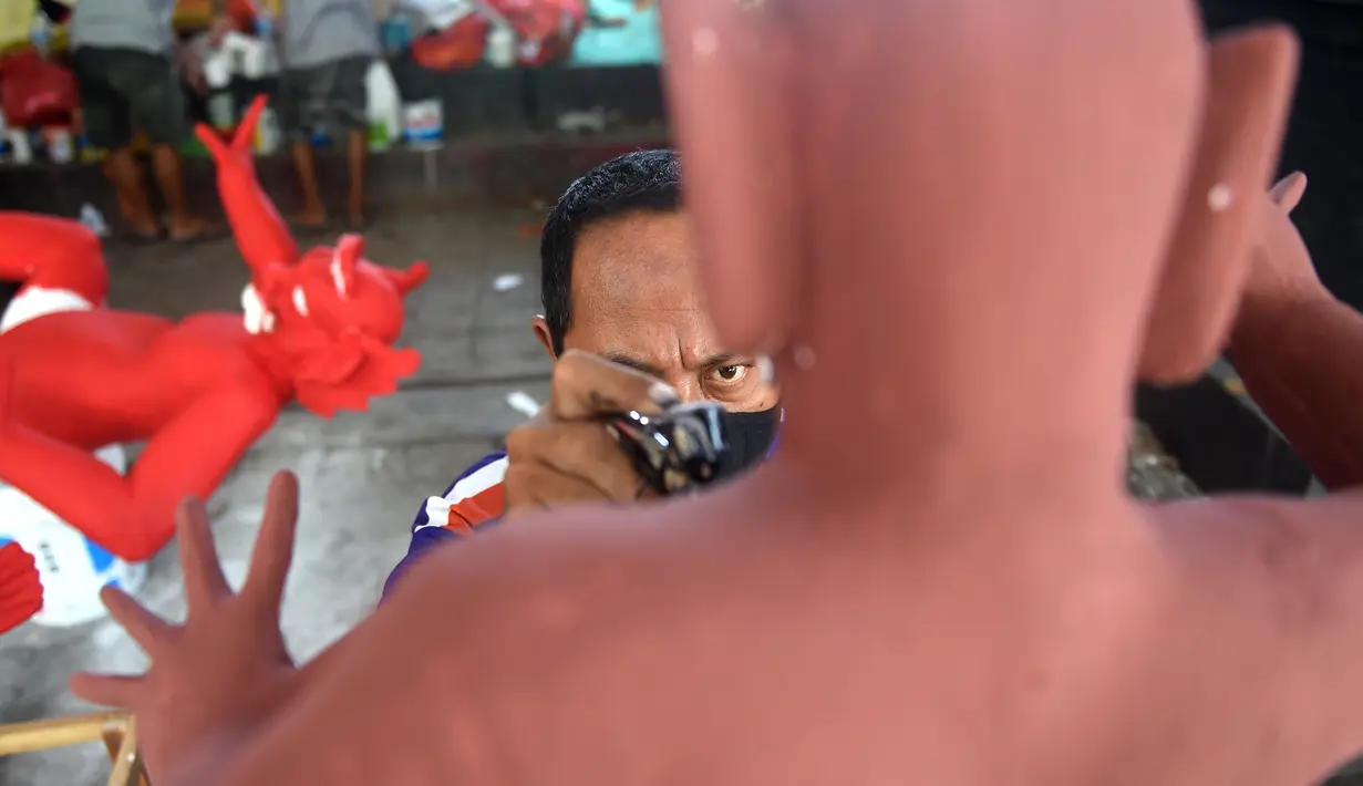 Seorang seniman menyelesaikan pembuatan patung atau yang dikenal ogoh-ogoh sebelum Perayaan Nyepi di Denpasar, Bali (12/3). Nyepi adalah hari raya umat Hindu yang dirayakan setiap tahun Baru Saka. (AFP Photo/Sonny Tumbelaka)