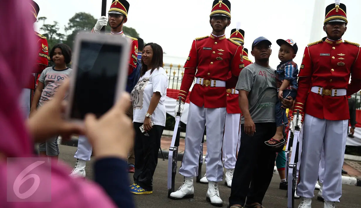 Warga berfoto bersama anggota Paspampres yang melakukan prosesi pergantian jaga Istana Kepresiden di depan Istana Merdeka, Minggu (28/8). Prosesi pergantian yang diwarnai sejumlah atraksi itu mengundang perhatian warga. (Liputan6.com/Faizal Fanani)