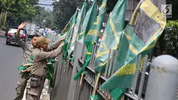 Petugas Satpol PP mencopot bendera partai politik di sepanjang pagar kawasan Pancoran, Jakarta. Selasa (18/7). Pencopotan dilakukan untuk menertibkan bendera partai politik liar yang memenuhi ruang publik di Ibukota. (Liputan6.com/Immanuel Antonius)