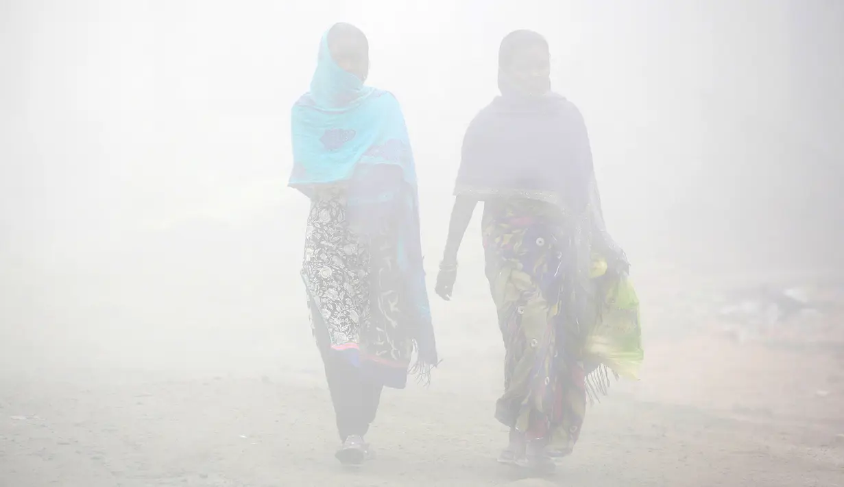 Warga berjalan melalui kabut tebal akibat polusi di Delhi, India (1/12). Sekitar 26 penerbangan ditunda atau dialihkan di Delhi sementara tiga dibatalkan, menurut situs IGI. (REUTERS/Cathal McNaughton)