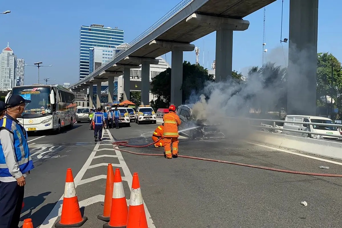 Sebuah mobil terbakar di Kilometer 5, Tol Dalam Kota Jakarta, pada Senin (26/7/2021).