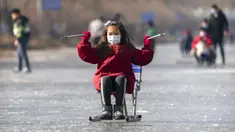 Seorang gadis yang memakai masker wajah untuk melindungi dari penyebaran virus corona COVID-19 menggunakan kursi untuk meluncur melintasi permukaan kanal yang membeku di Beijing, China, Sabtu (30/1/2021). (AP Photo/Mark Schiefelbein)