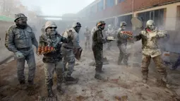 Orang-orang yang bersuka ria mengenakan pakaian militer tiruan saat ikut serta dalam perang makanan "Els Enfarinats" di Kota Ibi, Spanyol, 28 Desember 2022. Para peserta bertarung menggunakan tepung, telur, dan petasan. (JAIME REINA/AFP)