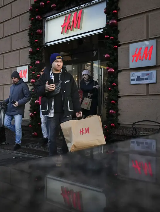 Seorang pria membawa kantong belanja setelah meninggalkan toko utama H&M di Moskow, Rusia, Rabu (30/11/2022). Di hari terakhir pembukaan, H&M menjual seluruh persediaan dengan diskon besar-besaran. (AP Photo/Alexander Zemlianichenko)