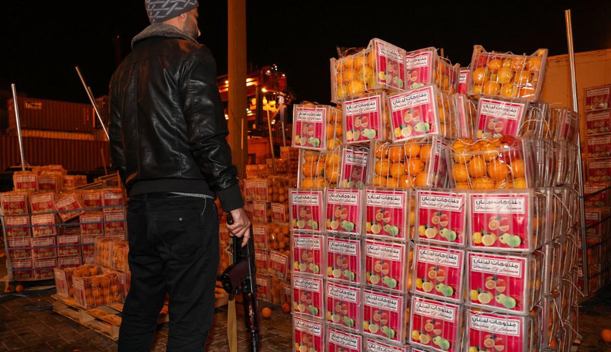 Seorang petugas bea cukai bersenjata memeriksa kotak jeruk palsu berisi pil Captagon di Pelabuhan Beirut, Lebanon, 29 Desember 2021. Bea Cukai Lebanon menyita sembilan juta pil Captagon dalam jeruk palsu yang ditujukan ke salah satu negara Teluk. (ANWAR AMRO/AFP)