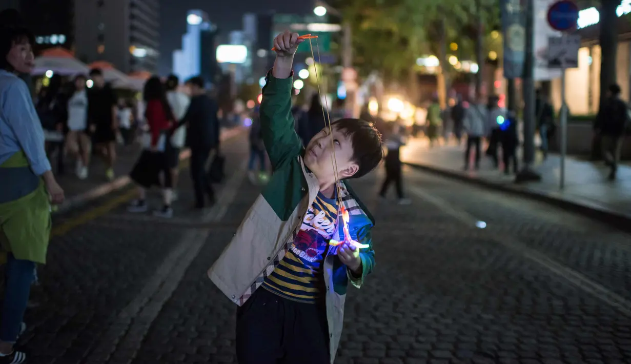 Seorang anak bersiap meluncurkan mainannya selama perayaan Chuseok di sebuah jalan di Seoul (5/10). Chuseok merupakan festival panen tahunan dan hari libur nasional selama seminggu di Korea Selatan. (AFP Photo/Ed Jones)