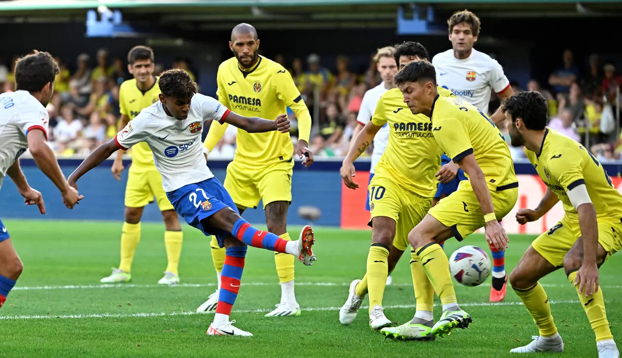 Pemain Barcelona, Lamine Yamal, melepaskan tendangan saat melawan Villarreal pada laga Liga Spanyol 2023/2024 di Stadion La Ceramica, Minggu (27/8/2023). Barca menang dengan skor 4-3. (AFP/Javier Soriano)