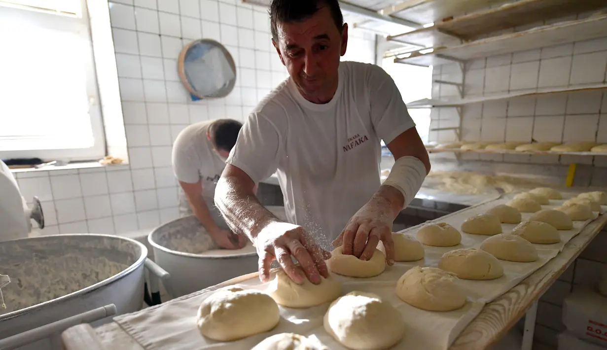 Pekerja membuat adonan somun di sebuah toko roti di kota tua Sarajevo, Bosnia and Herzegovina, Kamis (30/4/2020). Roti somun terbuat dari tepung, air hangat, dan garam sebagai penyedap. (ELVIS BARUKCIC/AFP)