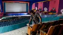 Pekerja membersihkan ruang bioskop sebagai persiapan kemungkinan pembukaan kembali setelah pelonggaran pembatasan Covid-19, di Chennai, Sabtu (3/10/2020). Kementerian Kesehatan India melaporkan pada Sabtu (3/10) total kematian di India akibat virus corona naik menjadi 100,842. (Arun SANKAR/AFP)