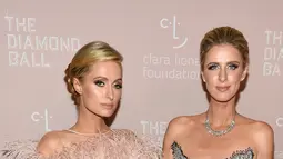 Model dan sosialita Paris Hilton (kiri) dan Nicky Hilton Rothschild saat menghadiri Diamond Ball ke-4 di Cipriani Wall Street, New York, AS, Kamis (13/9). Keduanya tampil dengan gaun merah dan biru. (Dimitrios Kambouris/GETTY IMAGES NORTH AMERICA/AFP)
