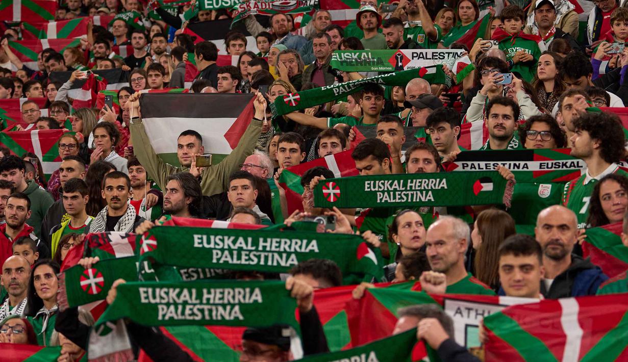 Ribuan penggemar juga berpartisipasi dalam demonstrasi besar di jalan-jalan Bilbao sebelum pertandingan, meneriakkan dukungan untuk Palestina. Tampak dalam foto, para pendukung mengibarkan bendera Palestina dan bendera wilayah Basque Utara selama pertandingan persahabatan antara tim pemain Palestina dan sekelompok pemain Spanyol dari wilayah Basque, yang diadakan sebagai protes terhadap aksi militer Israel di Gaza, di Bilbao, Spanyol, Sabtu 15 November 2025. (AP Photo/Miguel Oses)