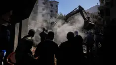 Orang-orang berkumpul saat sebuah ekskavator membersihkan puing-puing di lokasi serangan Israel pada Minggu 5 April 2026 terhadap sebuah bangunan di lingkungan Jnah, Beirut, Lebanon, Senin 6 April 2026. (AP Photo/Hassan Ammar)