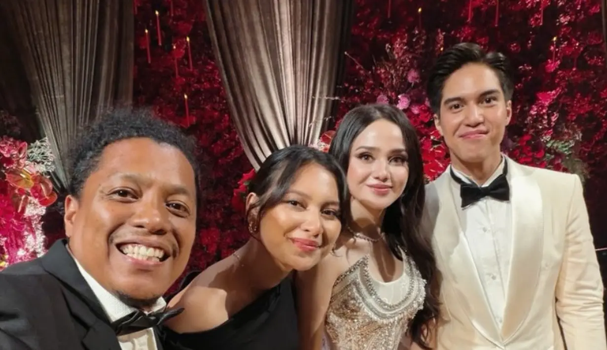 Indah Permatasari mengenakan long dress lengan panjang off shoulder hitam didampingi suaminya, Arie Kriting dengan setelan jasnya. [@indahpermatas]