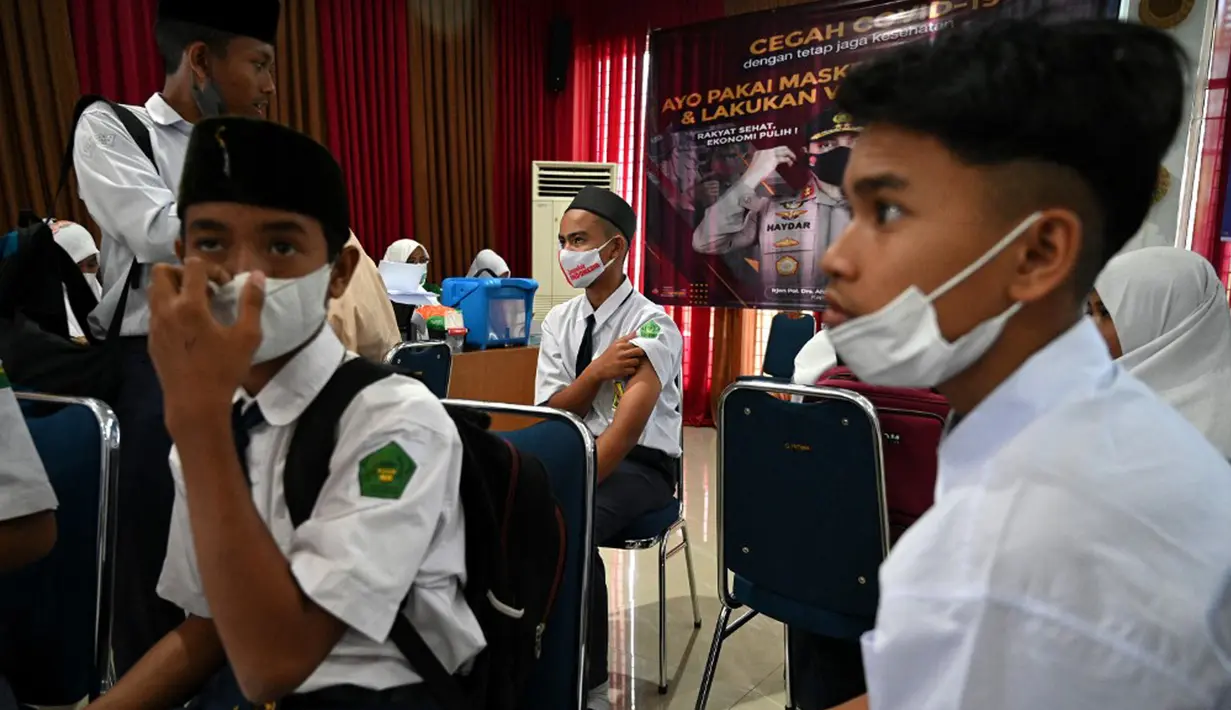 Sejumlah siswa sekolah menengah pertama menunggu untuk menerima dosis vaksin Sinovac pada acara vaksinasi virus corona COVID-19 di Blang Bintang, Provinsi Aceh, 21 September 2021. (CHAIDEER MAHYUDDIN/AFP)